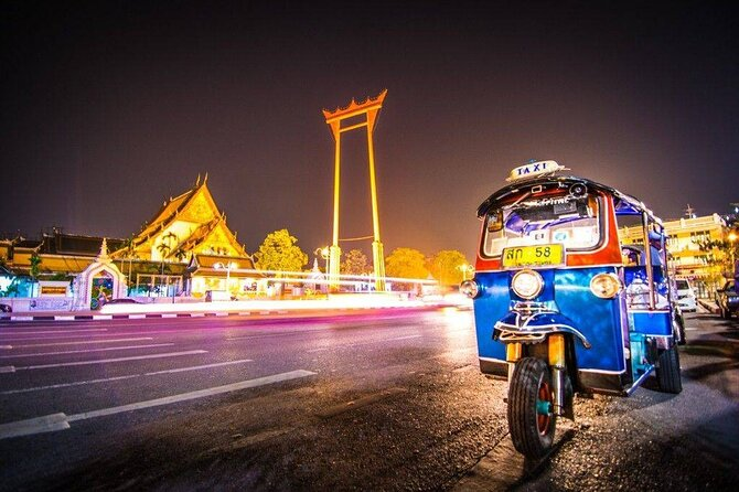 Private tuk-tuk on a lit-up street in Bangkok at night